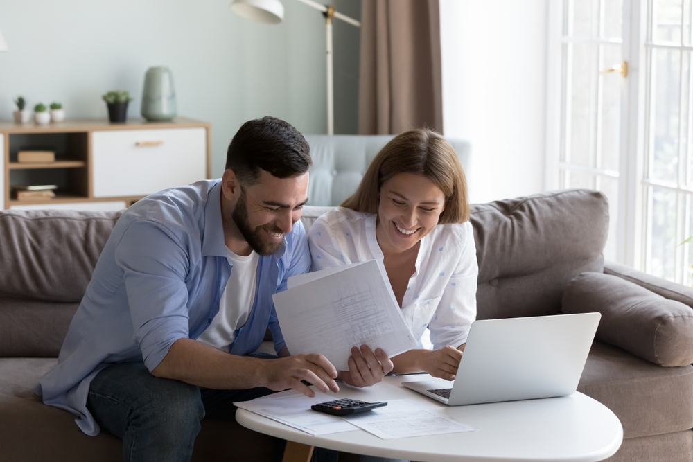 Cheerful,young,millennial,husband,and,wife,doing,domestic,paperwork,,accounting