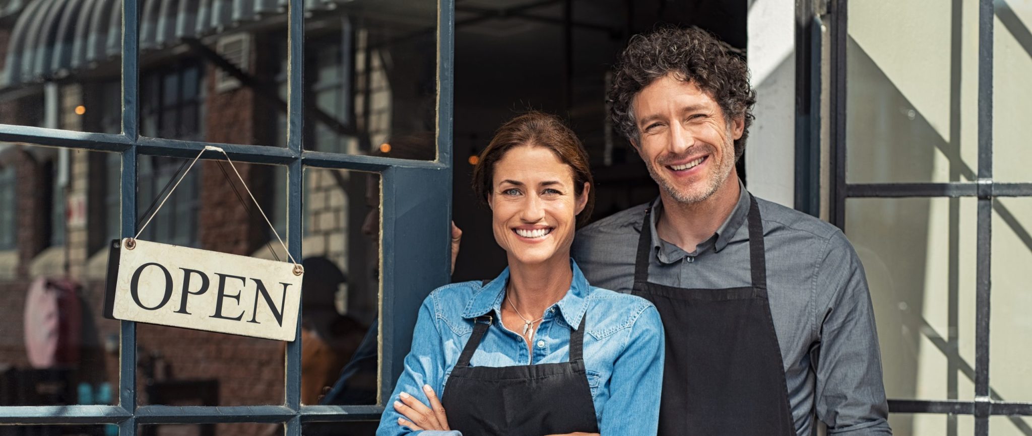 Two,cheerful,small,business,owners,smiling,and,looking,at,camera